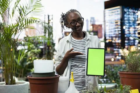 Green screen tablet used by smiling woman in rooftop garden Stock Photos