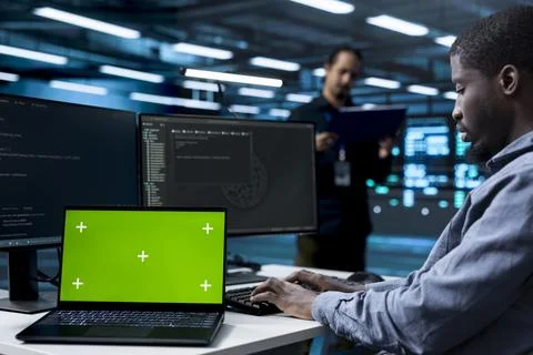 Green screen, technician and programming with laptop mockup in data center Stock Photos