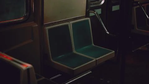 A green seat next to a window inside a subway train Illustrazione stock