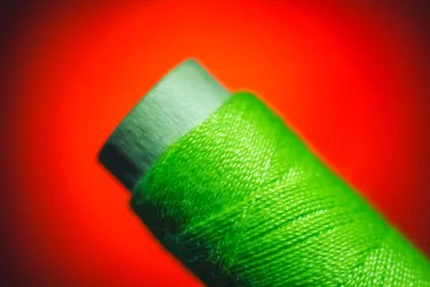 Green sewing thread closeup on red background Stock Photos