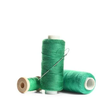 Green sewing thread spools with needle isolated on white background, closeup Stock Photos