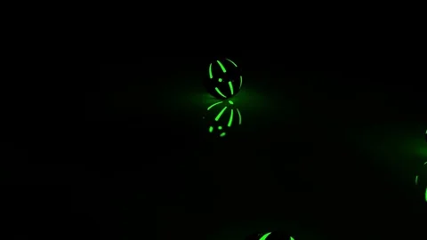 Green shining balls falling and rolling on a black background and floor Stock Footage 82794979