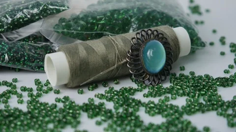 Green Shiny Beads Macro. Sewing Accessories with green thread and brooch Stock Footage 123073677