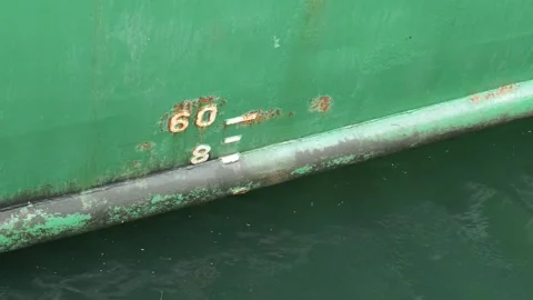 Green ship hull with draft marks floating on water Stock Footage 341787409