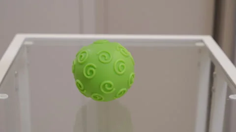 Green Silicone Ball Drops Unexpectedly onto Clear Glass Tabletop Stock Footage 321436665