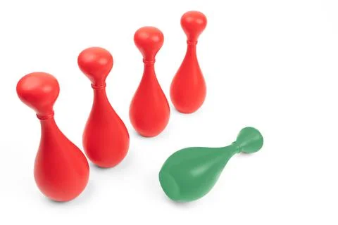 Green skittle lying down in front of four red ones on white background. Manager Stock Photos