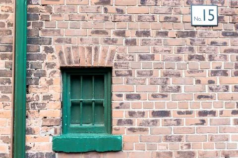 Green small retro window with bars in an old building with brick wall Stock Photos