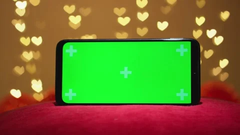 Green smartphone screen chroma key effect on background with hearts blurred Stock Footage 257910632