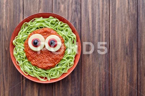 Green spaghetti creative pasta scary halloween food vampire monster with fake Stock Photos