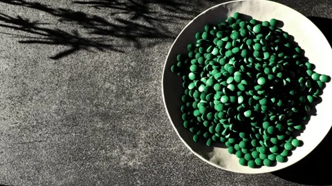 Green  spirulina tablets plate. Algae supplements. Superfood Stock Footage 317634716