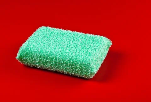 Green sponge on red background Foto stock