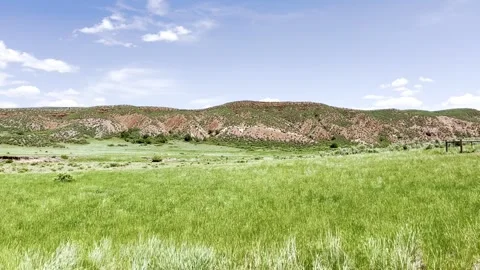 Green spring meadow below eroded red sandstone hills in high desert Stock Footage 339633878