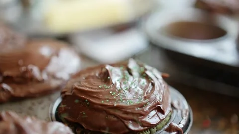 Green sprinkles falling in slow motion on chocolate frosting cupcake Stock Footage 150674981