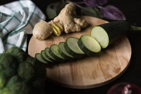 A green squash and the ginger root are lying on a wooden cutting board. in the Stock Photos