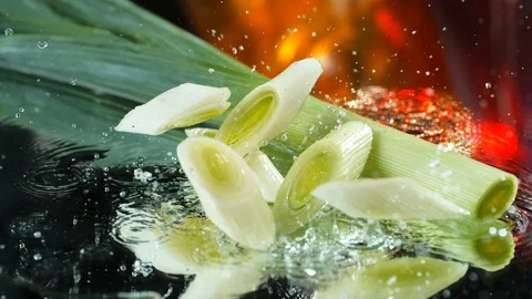 Green stems of leek slices falling into the water table in SLOW MOTION , 4k Stock Footage 114976491