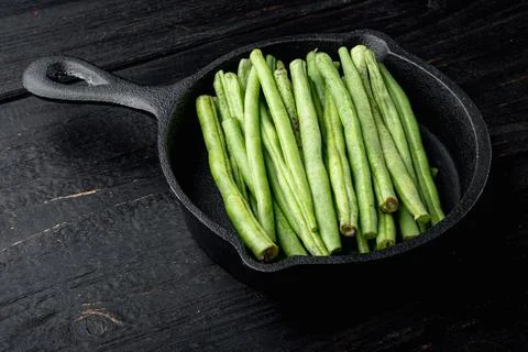 Green string bean, in frying cast iron pan, on black wooden table background, Stock Photos