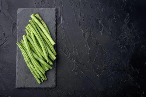 Green string bean, on stone board, on black background, top view flat lay, wi Stock Photos