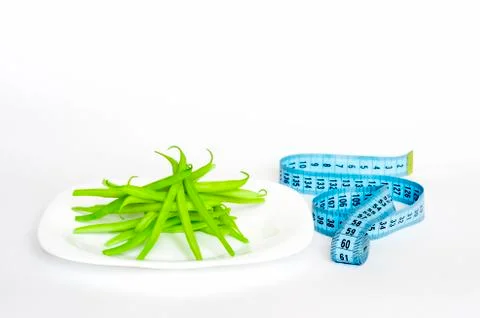Green string beans as a salad ingredient on a white plate with a blue measuri Stock Photos