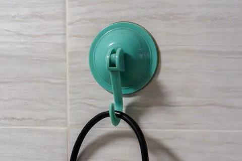 Green suction cup hook attached to tiled wall 库存照片
