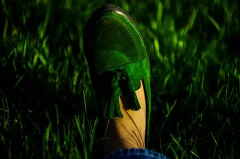 Green suede loafers on grass background. Bokeh. Horizontal Stock Photos