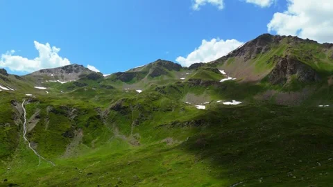 Green summer meadows in the mountains, seen from a drone flying toward the peaks Stock Footage 337512006