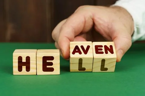 On a green surface, a man puts cubes with the inscription - heaven, hell Stock Photos