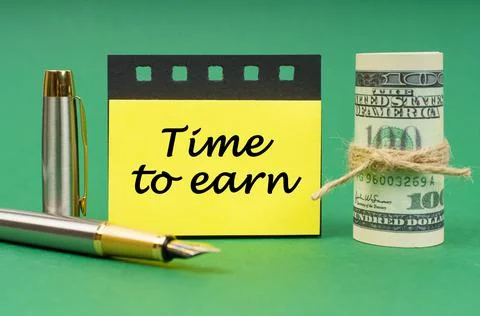 On a green surface, a pen, dollars, a notepad and yellow stickers with the in Foto stock
