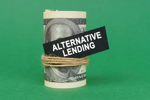 On a green surface, rolled dollars with a black sign that says - ALTERNATIV.. Stock Photos