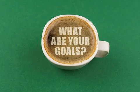 On a green surface there is a white cup with coffee, on the coffee foam the.. Stock Photos