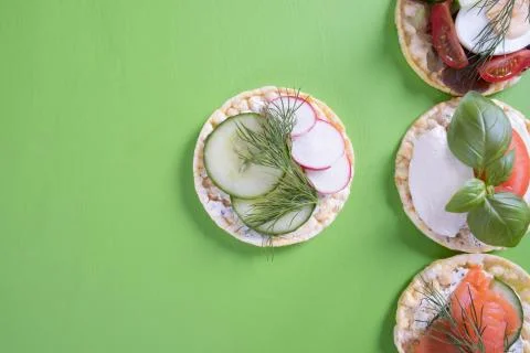 On a green table are corn waffles and on it are tomatoes, salmon, egg, radish Stock Photos