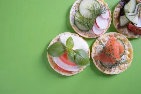 On a green table are corn waffles and on it salmon, egg, radish, cucumber Stock Photos