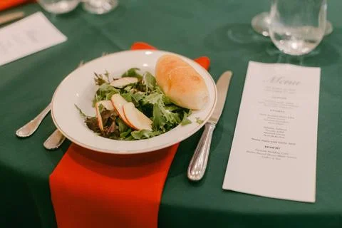 Green table setting with salad and bread in elegant dining environment during Stock Photos