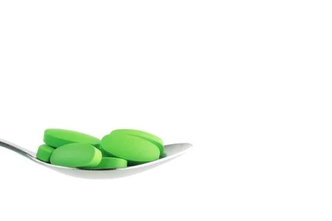 Green tablet on the spoon Stock Photos