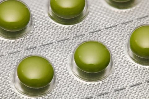 Green tablets in blister pack arranged with beautiful pattern. Global healthc Stock Photos