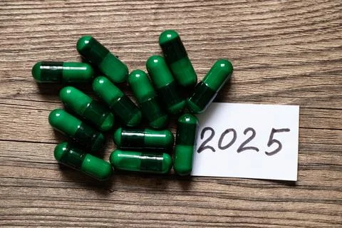 Green tablets in capsules are lying on the board and next to them is a card w Stock Photos