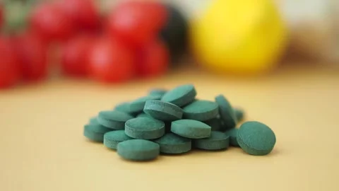 Green tablets on a table with fruits in the background Stock Footage 341647691