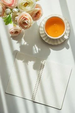 Green Tea Cup with Notebook and Ranunculus Flowers on White Table 스톡 사진