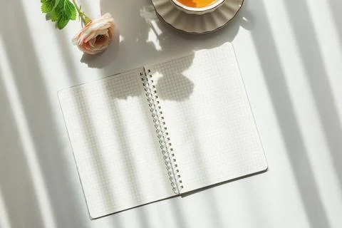Green Tea Cup with Notebook and Ranunculus Flowers on White Table 스톡 사진