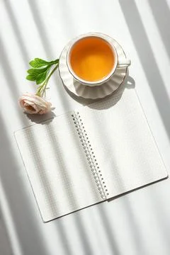 Green Tea Cup with Notebook and Ranunculus Flowers on White Table Foto stock