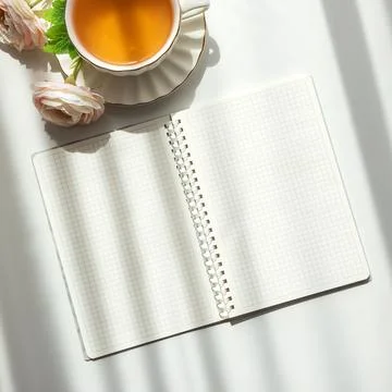 Green Tea Cup with Notebook and Ranunculus Flowers on White Table Foto stock