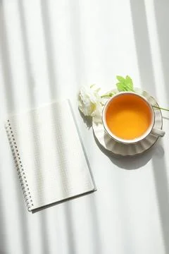 Green Tea Cup with Notebook and Ranunculus Flowers on White Table Stock Photos