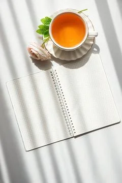 Green Tea Cup with Notebook and Ranunculus Flowers on White Table Stock Photos