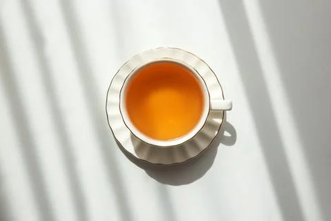 Green Tea Cup on White Table under Sunlight with Shadow Foto stock