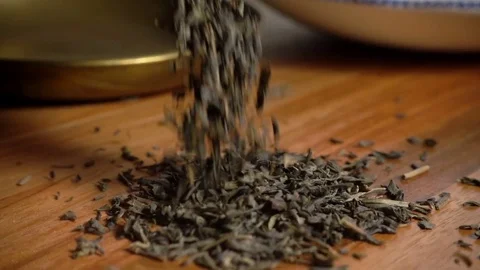 Green tea leaves piling up on wooden table, slow motion Stock Footage 77381553