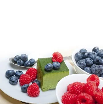 Green tea matcha mousse cake with raspberries and blueberries on top Stock Photos
