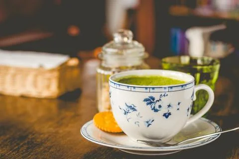Green tea matcha soy latte in a china cup with brown sugar and a glass of wat Stock Photos
