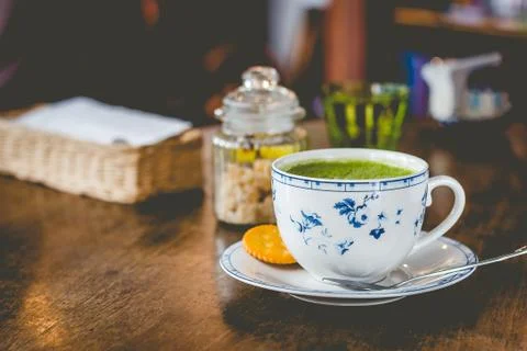 Green tea matcha soy latte in a china cup with brown sugar and a glass of wat Stock Photos