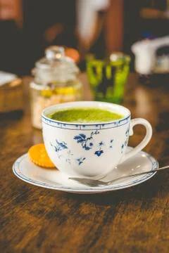 Green tea matcha soy latte in a china cup with brown sugar and a glass of wat Stock Photos