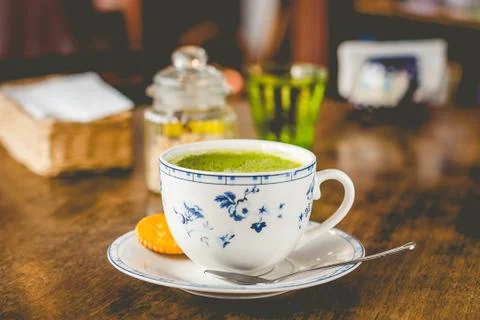 Green tea matcha soy latte in a china cup with brown sugar and a glass of wat Stock Photos