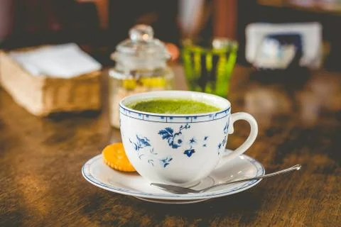 Green tea matcha soy latte in a china cup with brown sugar and a glass of wat Stock Photos